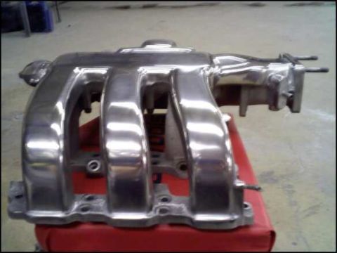 1994 Ford Probe - A shiny, polished intake manifold is shown resting on a red surface, with a watermark for SuperMotors.net visible.