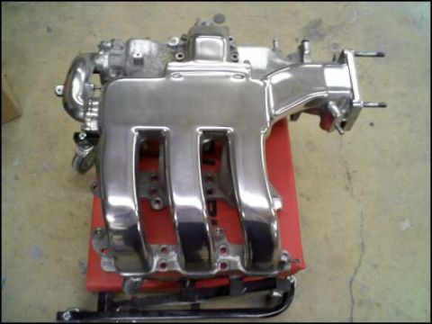 1994 Ford Probe - A shiny chrome intake manifold is shown, likely a replacement part for a vehicle.