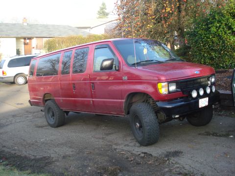 1994 Ford E350 - Red van with lifted suspension and off-road tires parked outside.