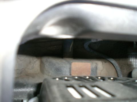 2000 Mercury Grand Marquis - Engine bay components are visible, including a black hose and wiring harness, with a metal grate in the foreground.