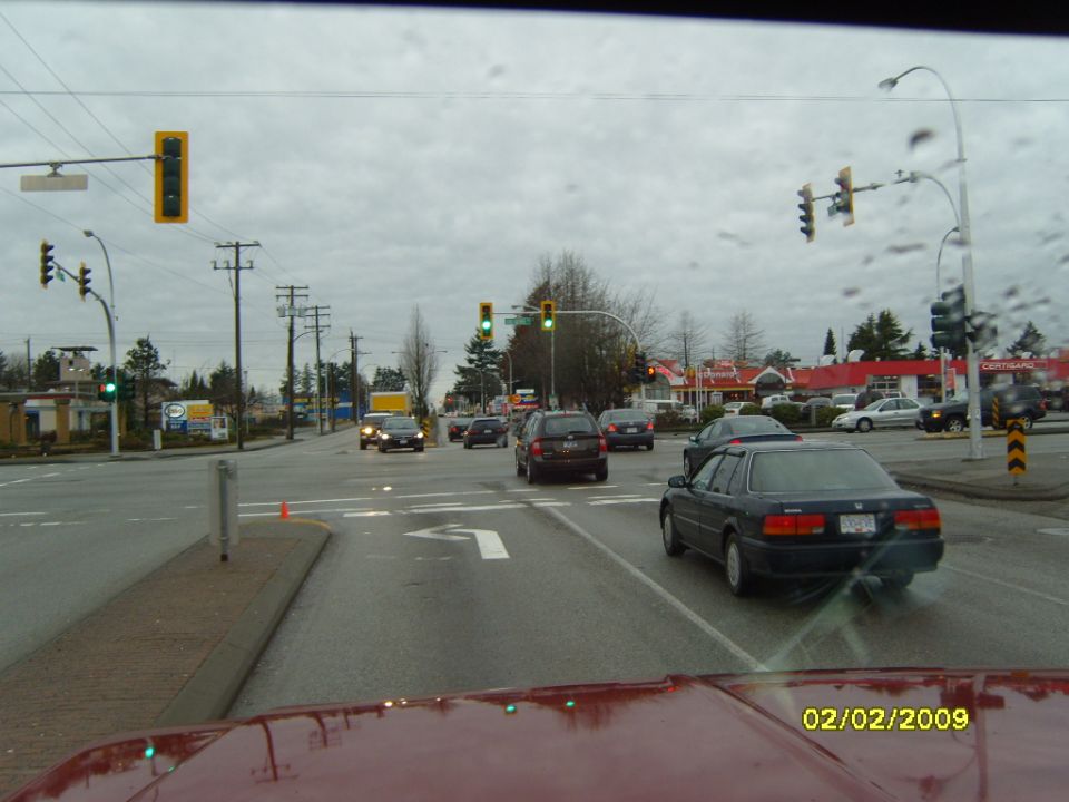 View from red car interior at intersection with multiple vehicles and traffic lights