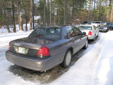 1991 Ford Crown Victoria LTD - A dark gray sedan is parked on a snow-covered road next to other vehicles.