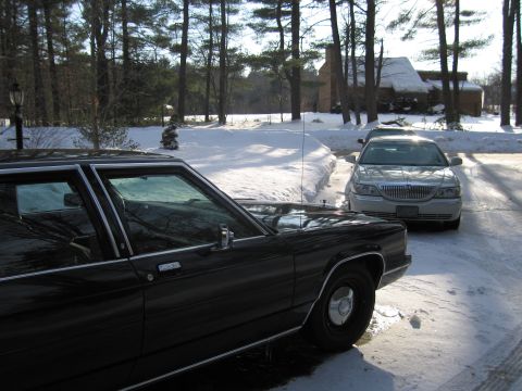 1991 Ford LTD Crown Victoria - Two sedans are parked in a snowy driveway on a sunny day.