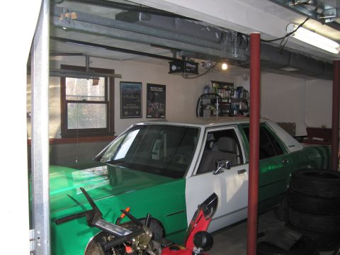 1991 Ford LTD Crown Victoria - A two-tone sedan is parked inside a garage with a window and shelves in the background.