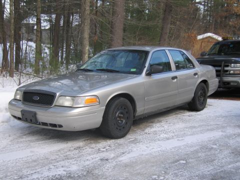 1991 Ford LTD Crown Victoria - A silver sedan is parked on a snowy driveway, with a dark SUV visible behind it.