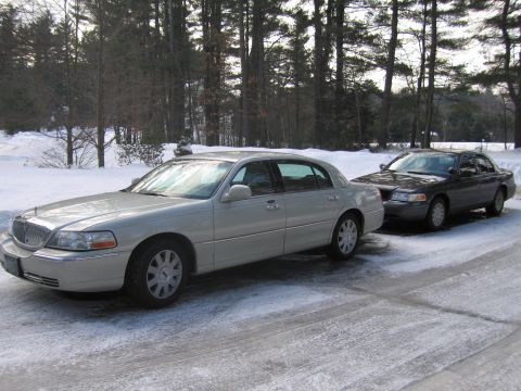 1991 Ford LTD Crown Victoria - Two sedans are parked on a driveway covered in snow and ice, with trees in the background.