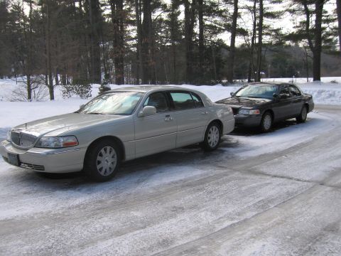 1991 Ford LTD Crown Victoria - Two sedans sit on a snow-covered road, with trees in the background.