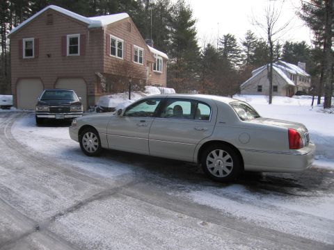 1991 Ford LTD Crown Victoria - A silver Lincoln Town Car is parked on a snow-covered driveway next to a black sedan.