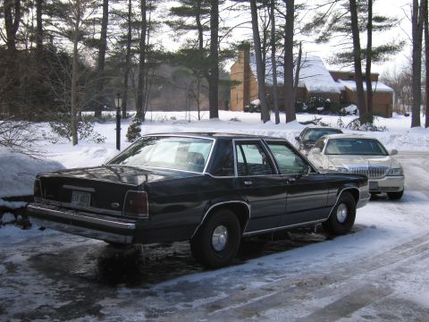 1991 Ford LTD Crown Victoria - A black 1991 Ford Crown Victoria LTD is parked on a snowy driveway next to another car.