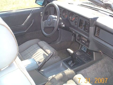 1984 Ford Mustang - The interior of a convertible shows the dashboard, steering wheel, and front seats.