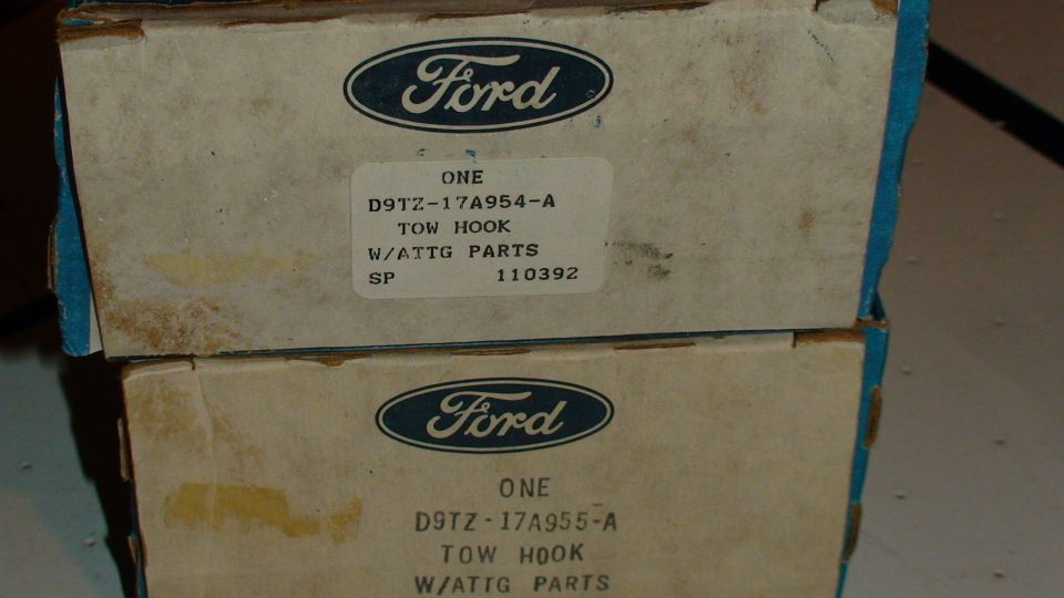 Two cardboard boxes with Ford logos, each containing a tow hook part