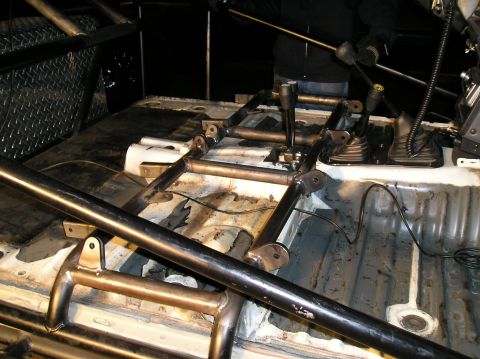 1986 Toyota Hilux - The interior of a vehicle shows a custom roll cage and dual gear shifters, indicating modifications.