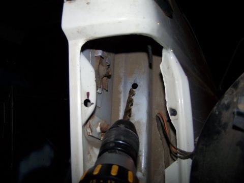 1990 Ford Bronco - A drill bit is shown entering a hole in the vehicle's bodywork during a repair or modification.