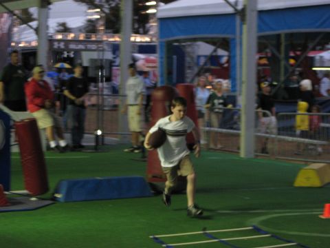 1973 Ford Torino - A young boy runs with a football across a turf field during an event.