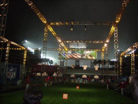 1973 Ford Torino - Nighttime view of Raymond James Stadium, the NFL logo and scoreboard under bright yellow lighting structures.