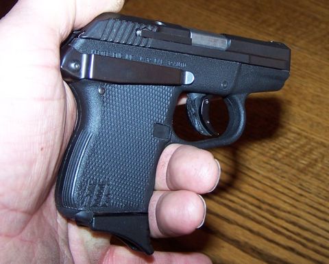 1990 Ford Bronco - A black semi-automatic pistol is held in a hand, showing its textured grip and extended magazine.