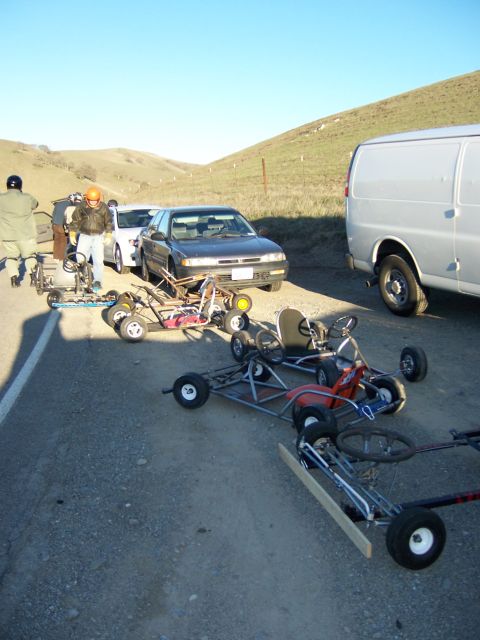 1991 Ford Bronco - A group of go-karts and support vehicles are gathered on the side of a rural road.