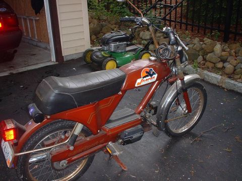 1981 Garelli Rally Sport - A vintage moped is parked in a driveway next to a lawn mower, with a car partially visible in a garage.