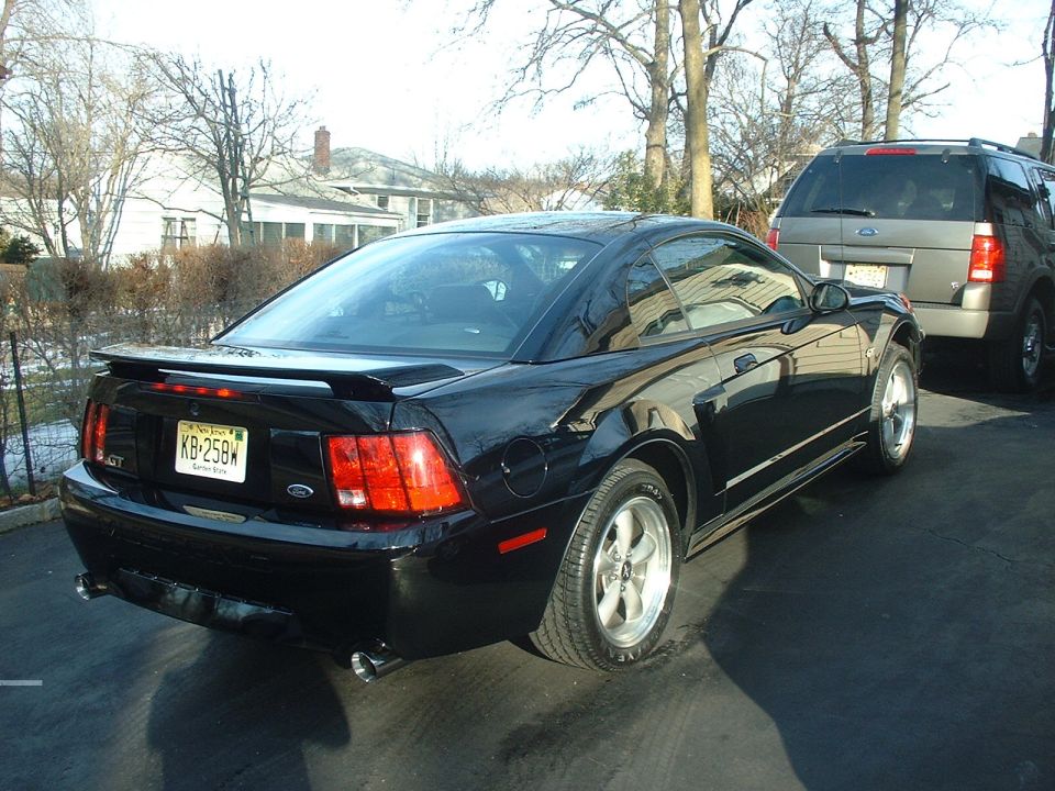 Black 2002 Ford Mustang GT rear quarter view with a gray SUV behind it