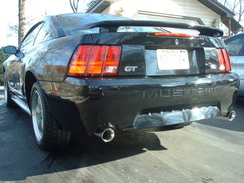 2002 Ford Mustang - The rear of a black Ford Mustang GT is shown parked in a driveway.