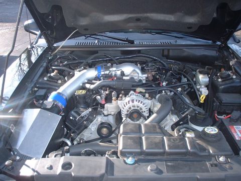 2002 Ford Mustang - The engine bay of a 2002 Ford Mustang shows a V8 engine with an aftermarket cold air intake system.