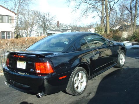 2002 Ford Mustang - Rear view of a black 2002 Ford Mustang coupe with a spoiler and custom exhaust tips.