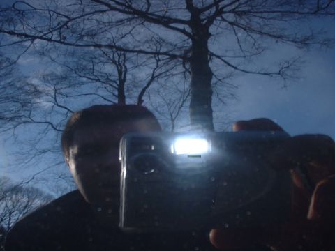 2002 Ford Mustang - A person holds a digital camera, its flash illuminating the scene reflected on a dark surface.