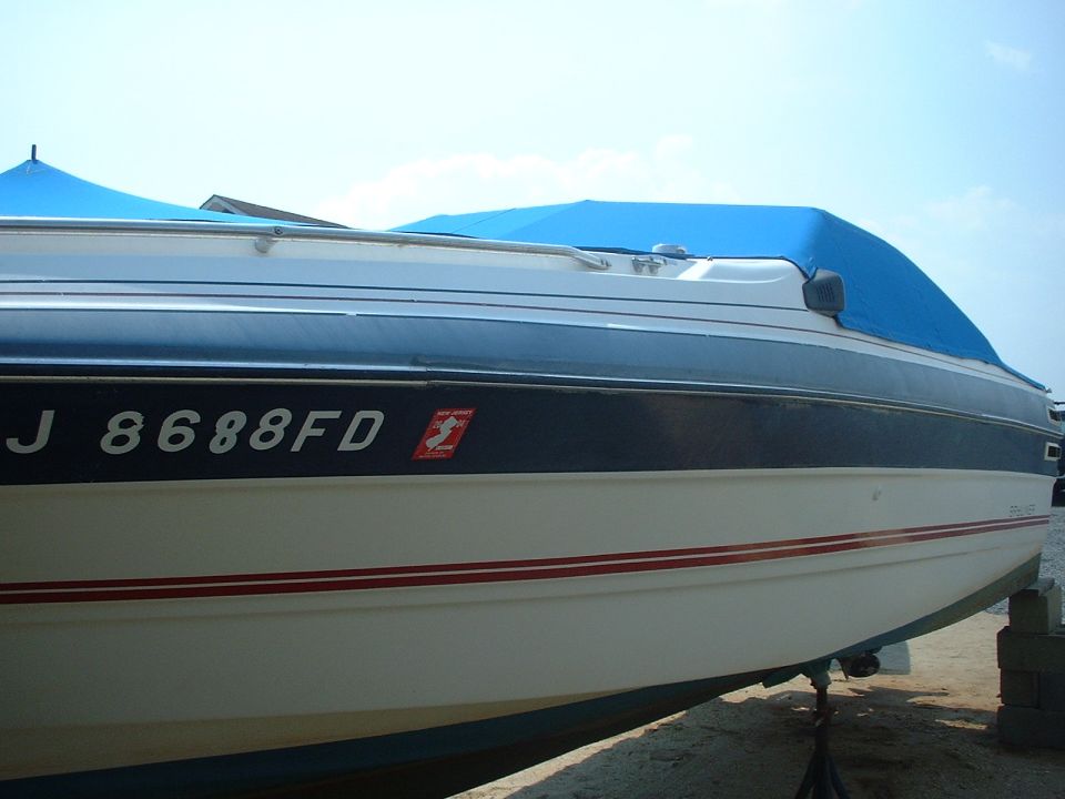 White powerboat with blue cover, black hull stripe and 'J 8688FD' registration, on a trailer.