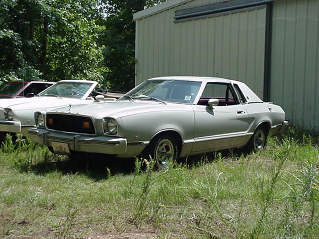 1976 Ford Mustang II coupe parked next to another car, with a building behind