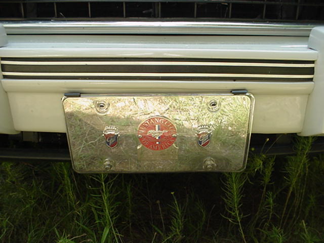 Chrome license plate frame with red and blue emblems, one reads 'MUSTANG CLUB OF AMERICA'