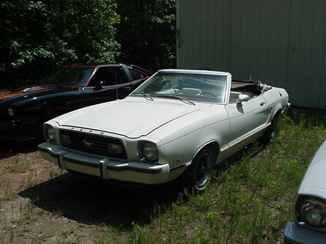 White convertible parked next to a black car with red trim