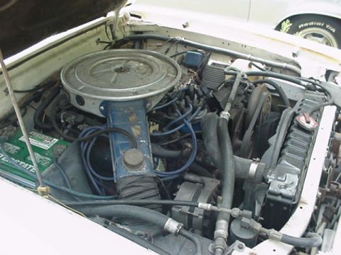 1977 Ford Mustang II - The engine bay of a vehicle is shown, with a V8 engine, air cleaner, and radiator visible. Another vehicle is partially visible in the back…