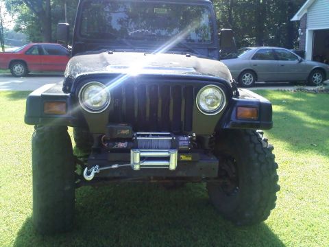 1995 Ford Bronco - A black Jeep Wrangler is parked in a driveway with two other vehicles visible in the background.