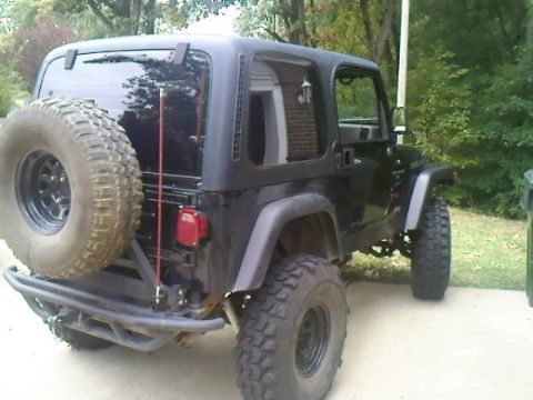 1995 Ford Bronco - Rear view of a black Jeep Wrangler with off-road tires and a spare tire on the back.