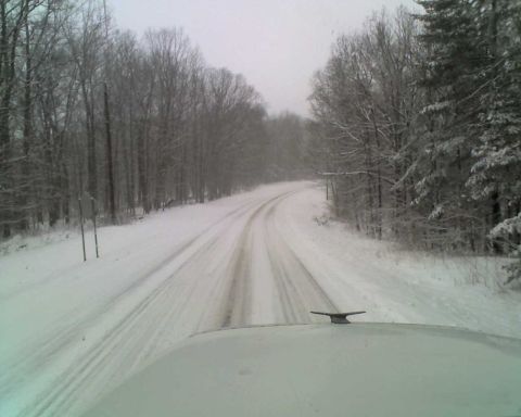 1995 Mercury Grand Marquis - A view from inside a vehicle driving on a snow-covered road through a forest.