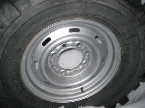 1990 Ford Bronco - A close-up view of a vehicle's wheel and tire, with snow on the ground.