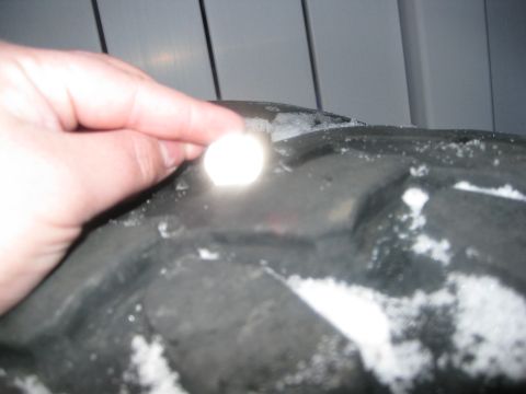 1990 Ford Bronco - A hand holds a coin against a tire tread covered in snow.