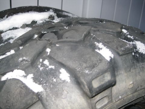 1990 Ford Bronco - This is a close-up of a tire with snow on it. The tread pattern is visible, and there is a watermark in the corner.
