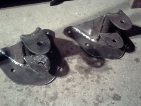 1996 Ford Bronco - Two custom metal brackets are shown on a concrete floor.