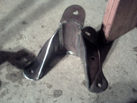 1996 Ford Bronco - A close-up view of a metal bracket with multiple mounting holes, resting on a concrete surface.