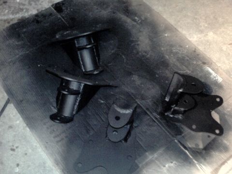 1996 Ford Bronco - Several black painted automotive suspension parts are laid out on a dark surface.
