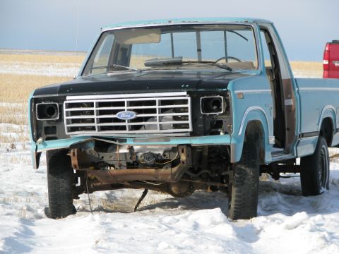 1982 Ford F-150 - Front view of a damaged light blue Ford F-150 truck in a snowy field.