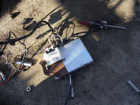 1992 Ford Bronco - Engine control module and wiring scattered on concrete, alongside a screwdriver and other parts.