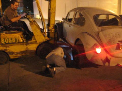1989 Ford Bronco - Forklift lifts a classic VW Beetle while a mechanic works on the rear axle.