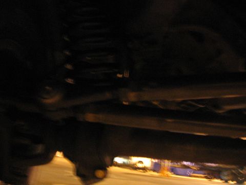 1989 Ford Bronco - A close-up shot of the undercarriage of a vehicle, showing suspension parts and the frame.
