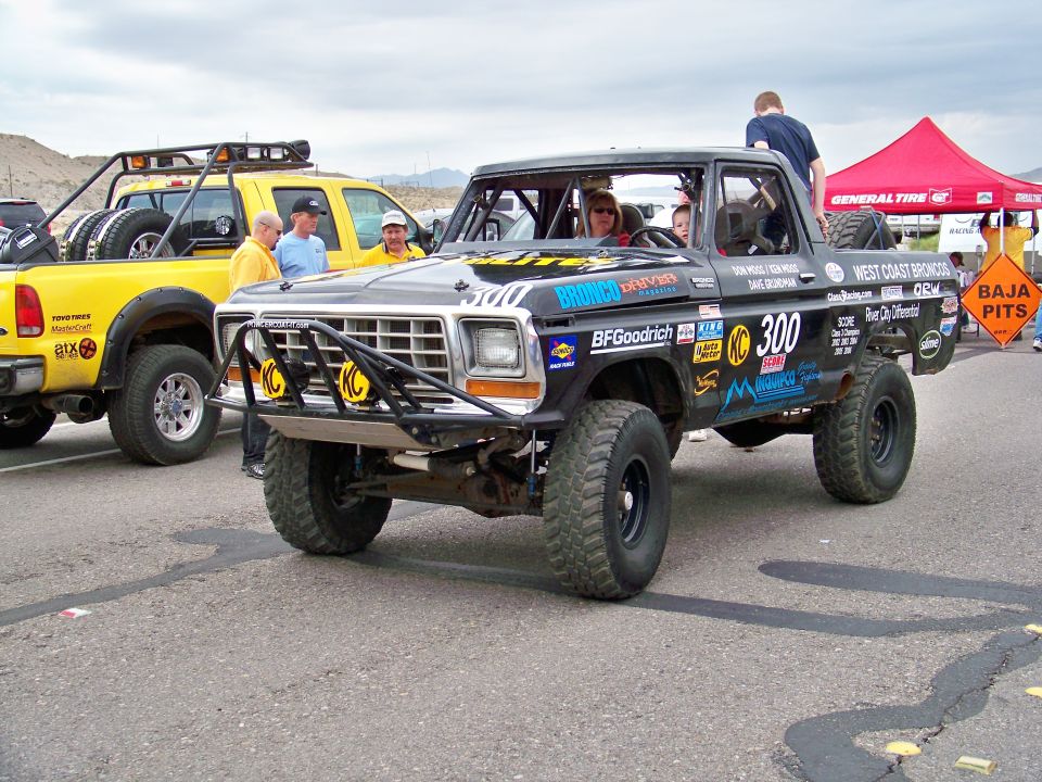 Black off-road race truck with roll cage, number 300, and various sponsor decals