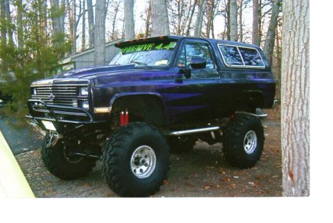 1987 Suzuki Samurai - This lifted SUV features a custom front bumper and off-road tires, suggesting a model from the 1980s.