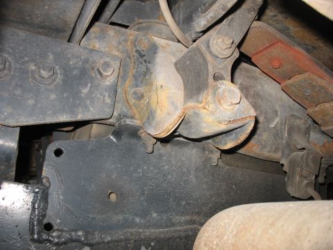 1995 Ford C-350 (Centurion Conversions) - Close-up view of a rusted and damaged rear spring hanger bracket on a vehicle's undercarriage.