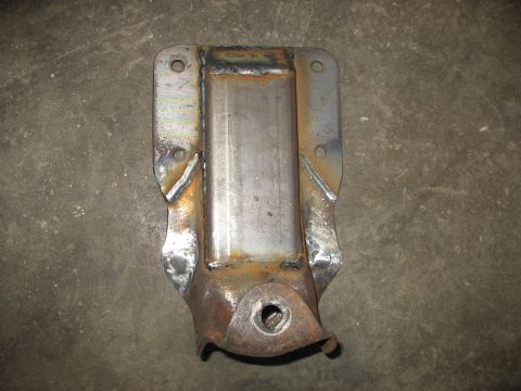 1995 Ford C-350 (Centurion Conversions) - Custom welded metal bracket, possibly a rear spring hanger, shown on a concrete surface.