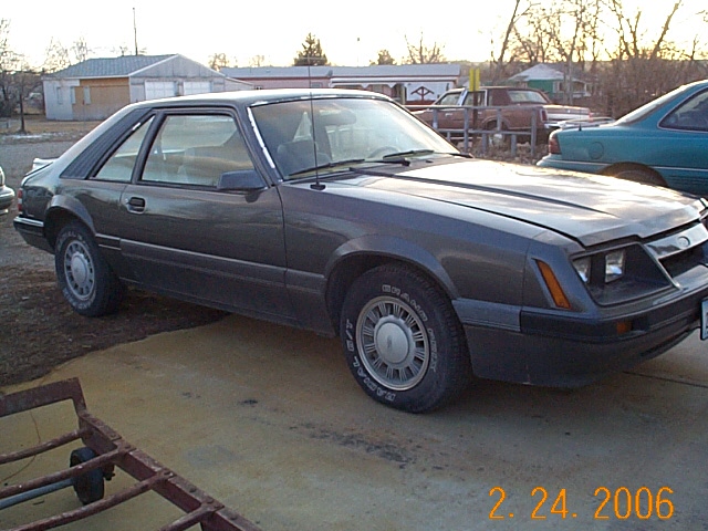 Gray Fox-body Ford Mustang hatchback, front quarter view, in a driveway